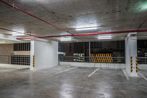 Parking garage interior in residential building at night with lighting. Car parking lot, traffic transportation, interior design concept.