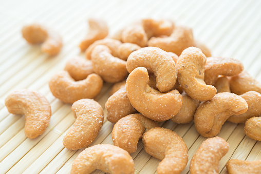 Salted cashew nuts on Japanese cooking mat background. Food, nutrition, healthy concept.
