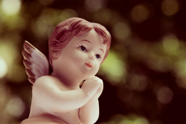 Cute angelic cupid statue with beautiful bokeh background in vintage style. Cute angelic cupid statue with beautiful bokeh background in vintage style. Valentine day, love romantic concept. winged cherub stock pictures, royalty-free photos & images