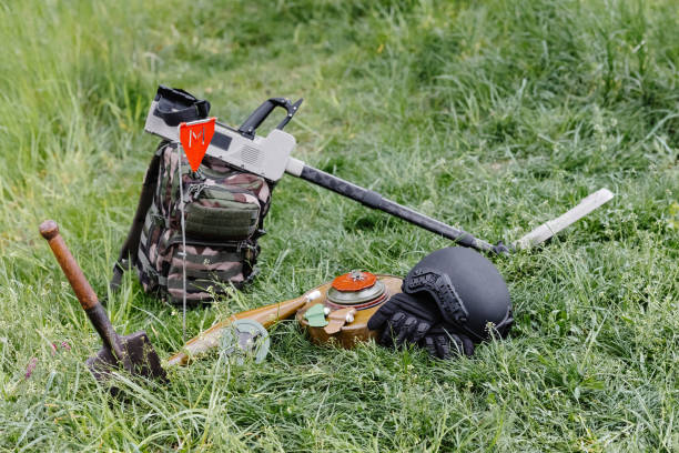 artefactos explosivos y un detector de metales se encuentran en el fondo de un macizo forestal. equipo para la remoción de minas del territorio - desminaje fotografías e imágenes de stock