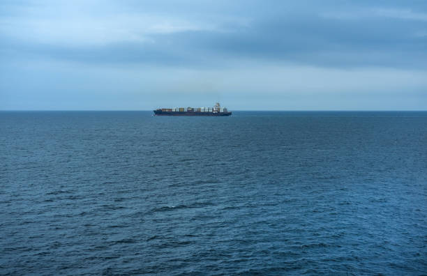 istock Distant view of a large cargo ship loaded with containers and other freight in the middle of the sea 1620656756