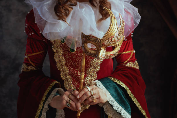 Closeup on medieval queen in red dress with venetian mask stock photo