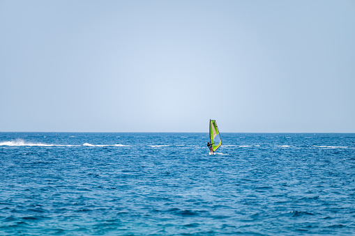 Young girl windsurfing in a blue sea in a summertime.