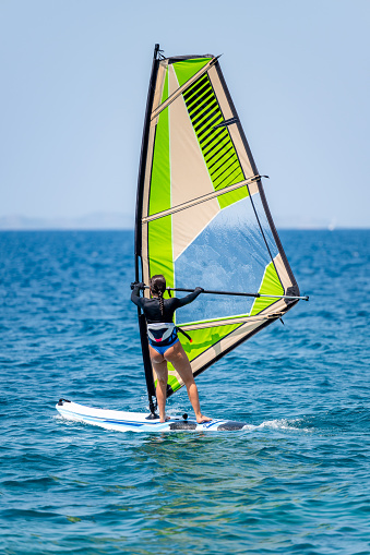 Young girl windsurfing in a blue sea in a summertime.