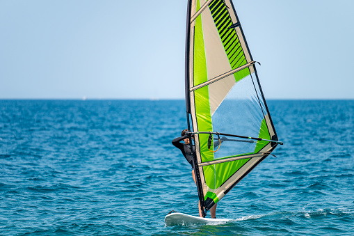 Young girl windsurfing in a blue sea in a summertime.