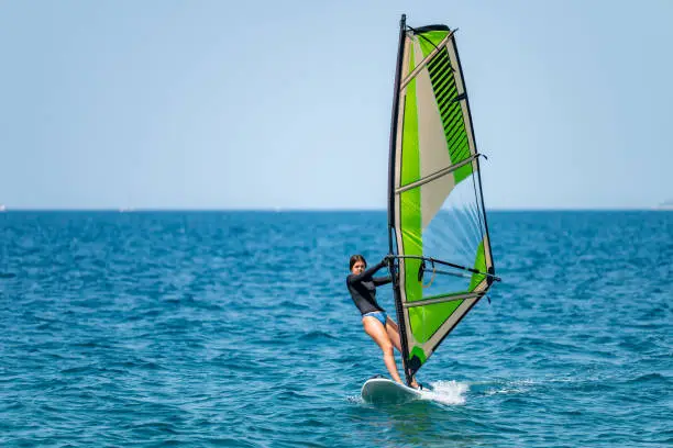 Young girl windsurfing in a blue sea in a summertime.