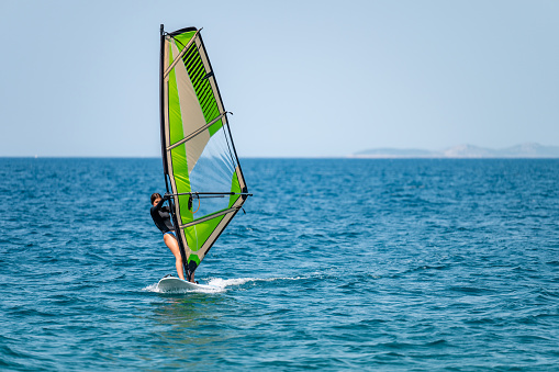 Man using windsurfing wing and a hydrofoil board while while engaging in extreme sports on the sea and ocean water. Kitesurfing.