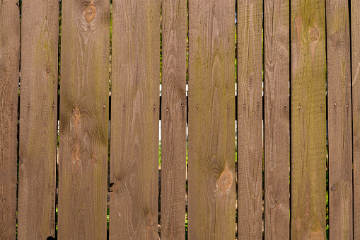 Close-up on an old wooden fence with a missing panel.