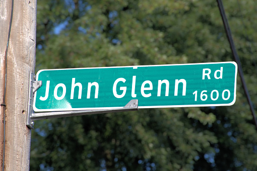 Dayton, Ohio USA August 8, 2023: Street sign over John Glenn Road  Glenn was an astronaut that flew on Mercury and Space Shuttle missions and served as a member of the United States Senate.