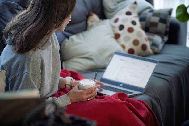 istock A woman wrapped in a blanket drinks coffee and uses laptop, on the sofa 1620695749