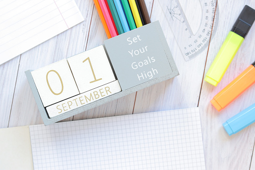 01 September. Image of a wooden calendar for September 1 on the table, top view. Autumn day. Back to school. Stationery and perpetual calendar