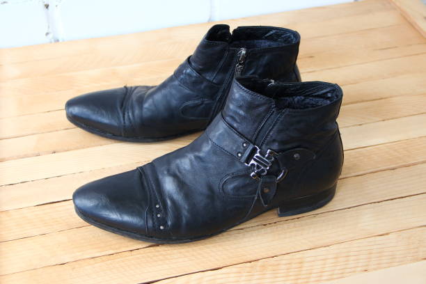 istock Black leather boots on a wooden background 1620732781