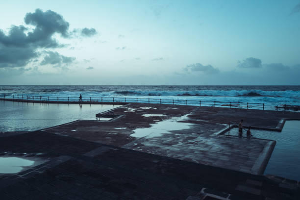 Punta del Hidalgo, Spain, April 5, 2023: People enjoys natural swimming pools by the sea at sunset on April 5, 2023 in Punta del Hidalgo, Tenerife, Canary Islands, Spain.