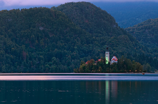 Small island with Pilgrimage Church of the Assumption of Maria on Bled Lake. Church reflection in water. The most famous lake in Slovenia. Blue hour. Travel and tourism concept.