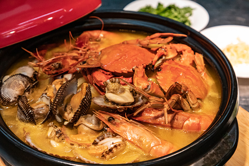 The cooked seafood from the restaurant kitchen is placed in a stone pot, and after pouring in the broth, it is being heated and bubbling