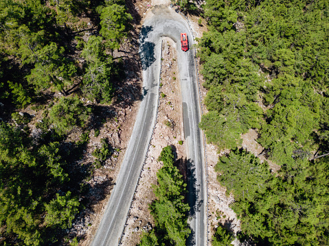 Big fire truck. Driving through woodland, asphalt road. Aerial drone shot. Curvy curvy road view.