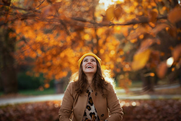 istock smiling trendy woman throws up autumn leaves 1620775966