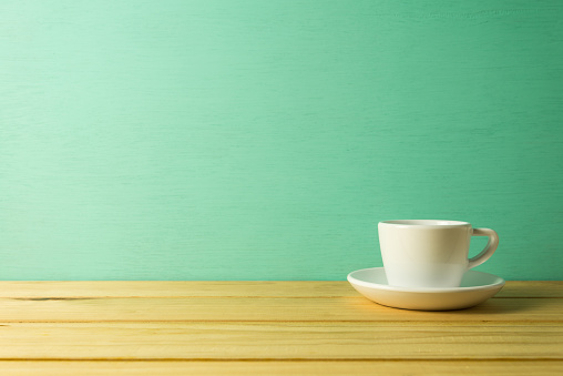 White coffee cup on table with green background with copy space. Drinking, cafe business, lifestyles concept.