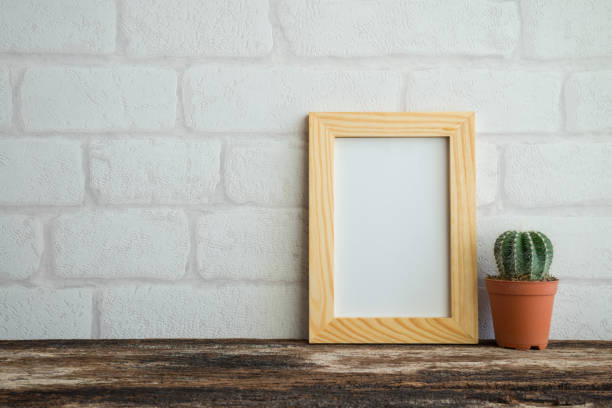 istock Photo frame and cactus pot on old wooden table with white wall background copy space. 1620784884