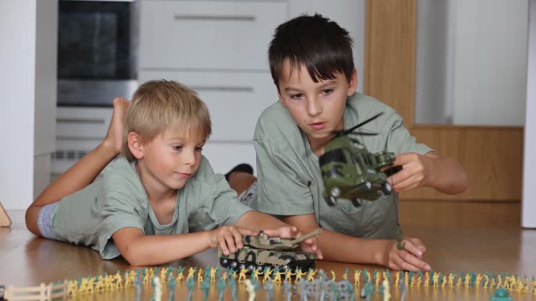 Happy children, siblings, boy, playing with tanks and soldiers at home. Bautirufl kids playing with plastic toys