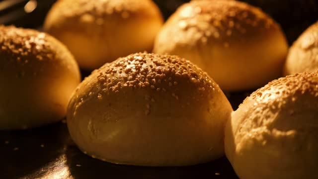 Buns baking in oven. Fresh buns with sesame. Bun for hamburger rising up in oven