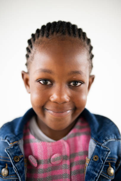 Portrait of a shy young girl of African ethnicity with a slight smile against a white background.