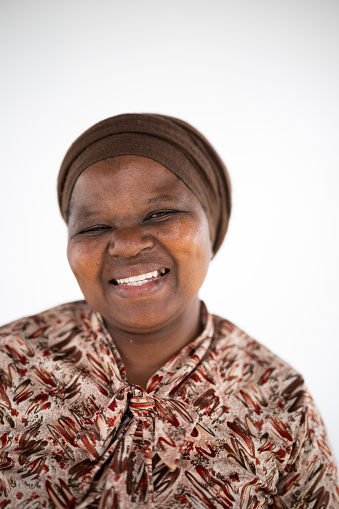 Portrait of a cheerful woman of African ethnicity wearing a headscarf against a white background.