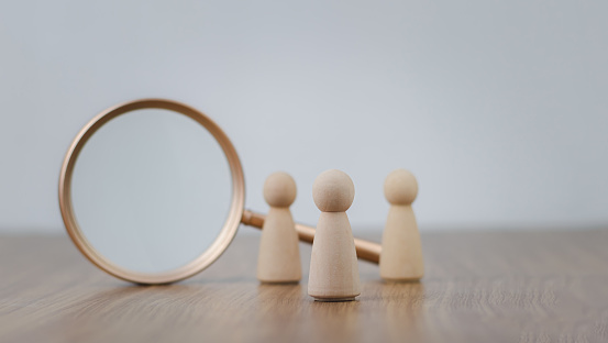Human Resource Management Network Structure (HRM), wooden human figure stands near a magnifying glass. Search for vacancies and work. search for people and workers, hiring, training, performance.