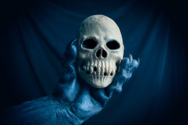 A monster hand holding a skull in the dark.