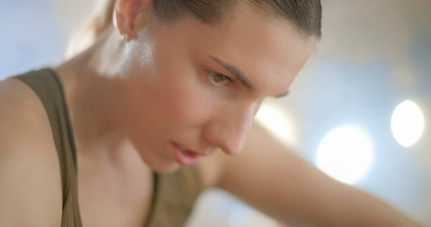 Close-up of tired athlete woman sitting on ground in sports hall.