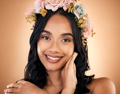 Portrait, skincare and flower crown with a model woman in studio on a brown background for shampoo treatment. Face, smile or beauty with a happy young person looking confident about natural cosmetics