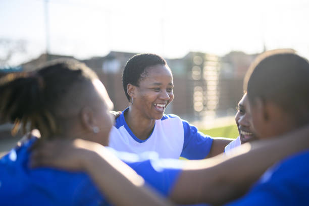 Female football players put hands together Female football team practicing together on community sports grounds transgender-athletes stock pictures, royalty-free photos & images