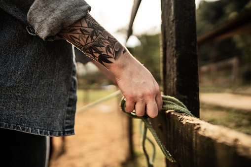Close-up of woman hands tying a rope on fence on a ranch
