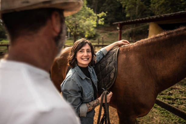 istock Daughter putting the saddle on horse and talking with her father on a ranch 1620876114