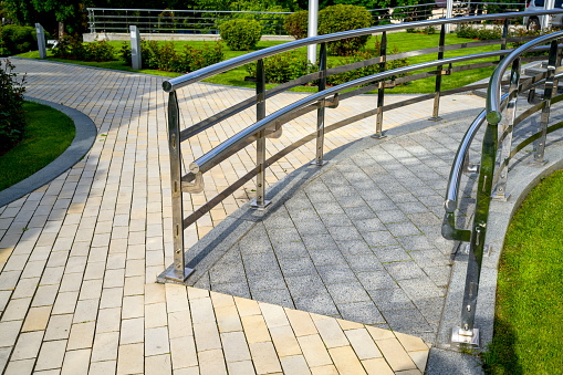walkway chrome railings, ascent and descent for wheelchairs, in the landscape design
