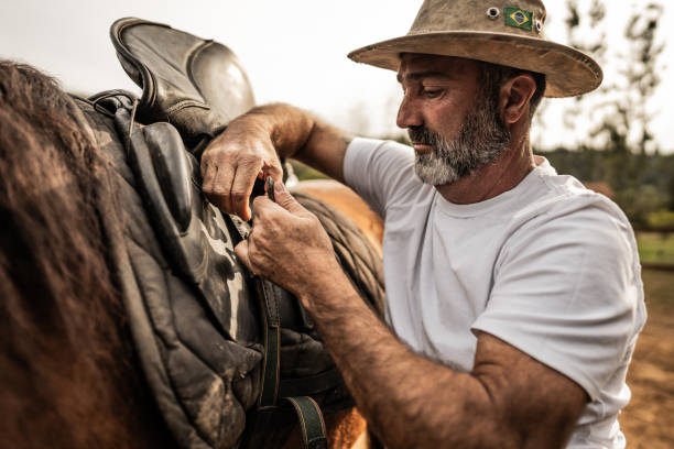 istock Mature man putting the saddle on his horse on a ranch 1620876679