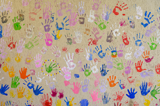 prints of children's hands in multi-colored paint on the wall, colored prints of the palms, close-up shot