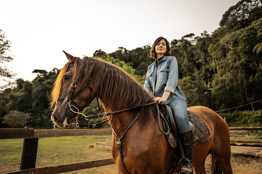 Portrait of a young woman horseback riding on a rural scene