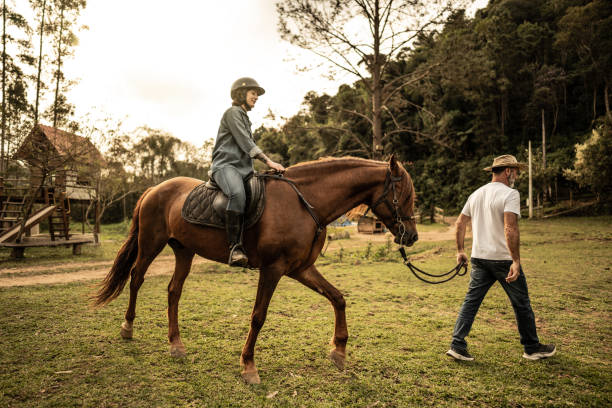 istock Father pulling the horse with her daughter on a stable 1620882747