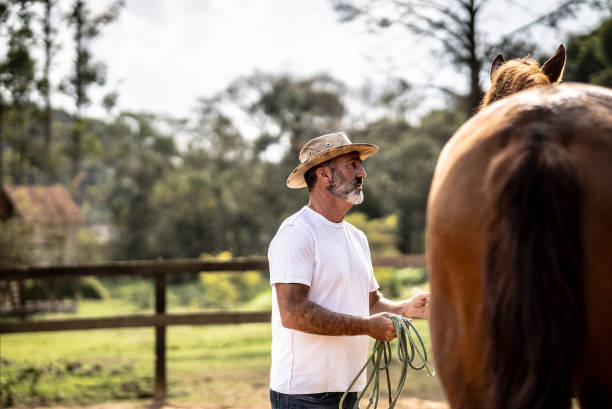 istock Mature man holding his horse on a stable 1620884449