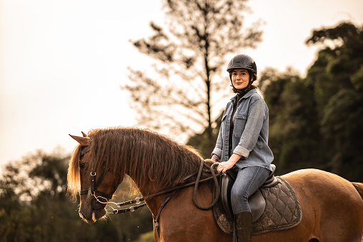 Portrait of a young woman horseback riding on a stable