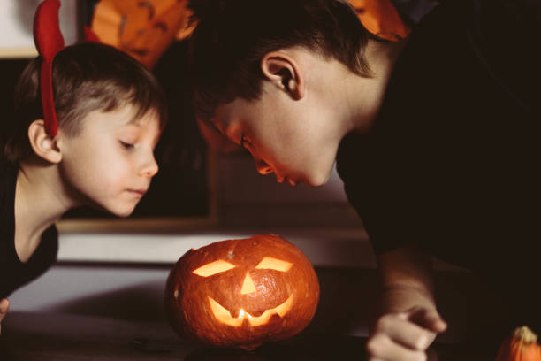 istock Little boys looking at self made traditional Jack lantern. Candle lame reflection on faces. Halloween concept 1620886277