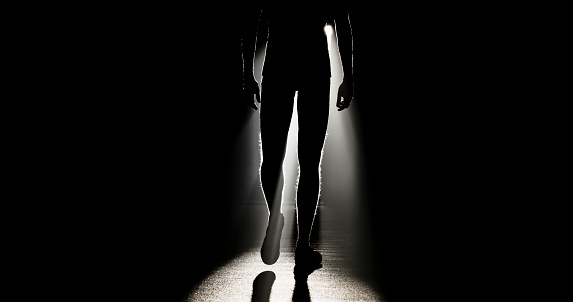 Silhouette of young man walking in sports hall during practice.