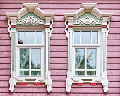 Wooden window with carved architraves on pink facade of tatar house early 20th, Kazan, Russia