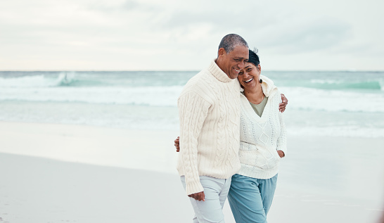 Senior couple, hug and beach walk together with funny moment, comic memory or conversation by sea. Happy retirement, ocean and outdoor embrace with love, bond or romance for laugh by waves on holiday