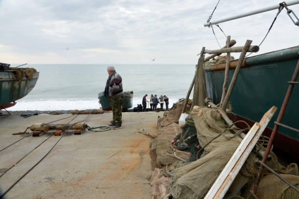 Sochi, Adler, Russia - January 7, 2022: Fishermen at the pier are taking over the catch of mullet fish. Adler, Sochi, Russia.