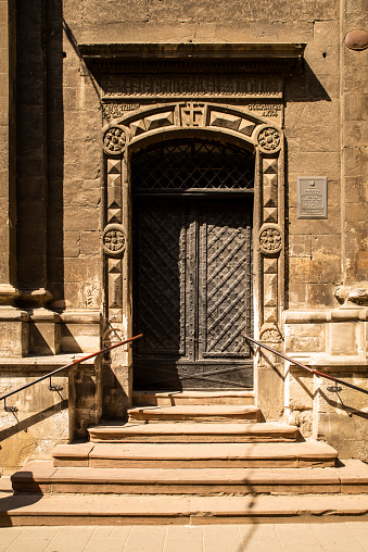 Entrance street carved wooden doors with metal inserts and hinges, large part of the building as an element of architecture large