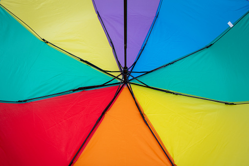 Closeup rainbow umbrella with natural blurred background. soft and selective focus, lgbt and pride month concept.