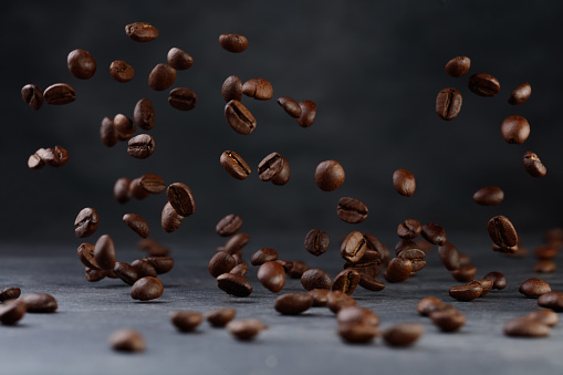 Levitating Coffee Beans. Grains of roasted coffee falling on gray stone background. Shallow depth of field