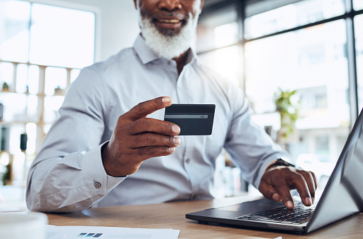 Hands of black man, business credit card and laptop for ecommerce, finance or accounting in office. Worker, computer and financial payment of budget, fintech trading or banking of investment economy
